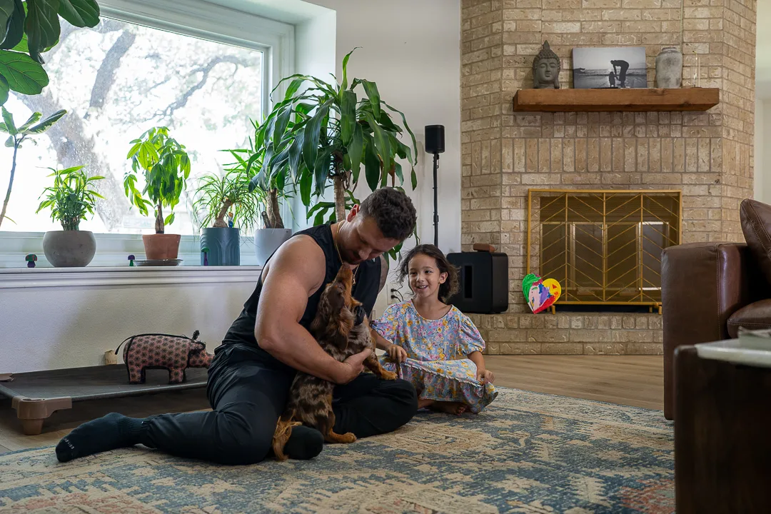 Isaac training with his daughter and a dog in their home